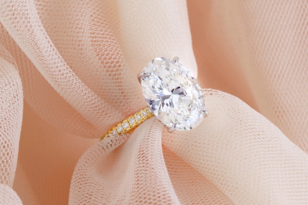 close up image of an oval cut, yellow gold engagement ring on a piece of pink tulle