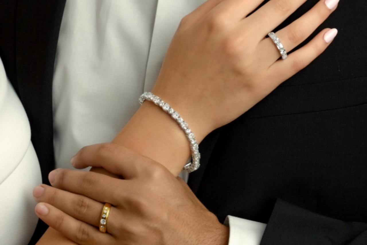 a close up on a bride and groom’s wedding bands and the bride’s diamond tennis bracelet